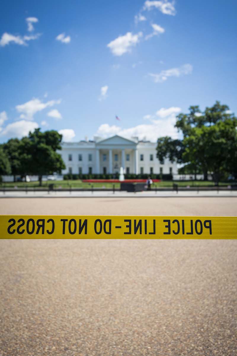 washington Police line-do not cross stanchion near trees under blue sky at daytime the white house